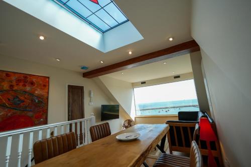 ein Esszimmer mit einem Tisch und einem Dachfenster in der Unterkunft Fleur de Sel - Upside Down Cottage with Spectacular View & Parking in Brixham