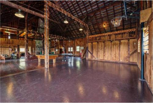 an empty barn with a wooden floor and a basketball hoop at The Barn at Evermore: riverfront retreat w/hot tub in Luray