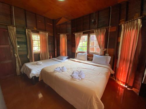 a bedroom with two beds with towels on them at สวนดวงมณี รีสอร์ท in Ban Tha Thong Mon