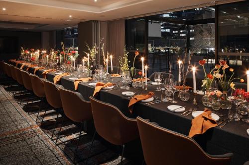 a long table in a room with chairs and lights at Rydges Melbourne in Melbourne