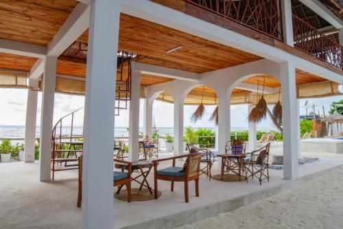 an outdoor patio with tables and chairs and the ocean at Kupaga Villas Boutique Hotel - Adults Only in Jambiani