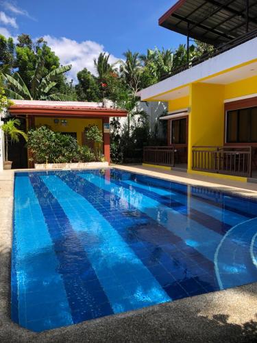a swimming pool in front of a house at Villas de piscina in Sipalay