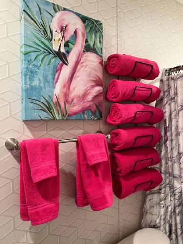 a towel rack with pink towels and a painting of a flamingo at Pink Flamingo House in Cocoa