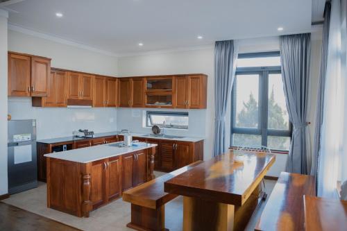 a kitchen with wooden cabinets and a large window at SEN VILLA Boutique in Bao Loc