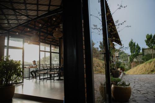 a glass door of a house with a person sitting at a table at SEN VILLA Boutique in Bao Loc