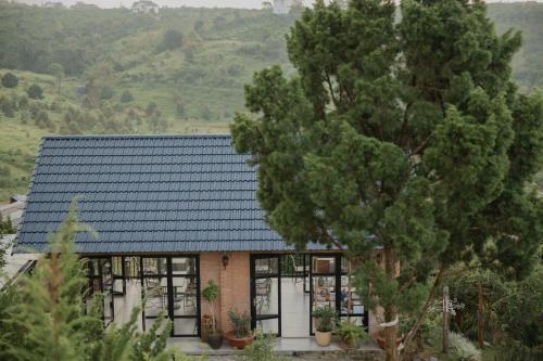 a house with a blue roof and a tree at SEN VILLA Boutique in Bao Loc