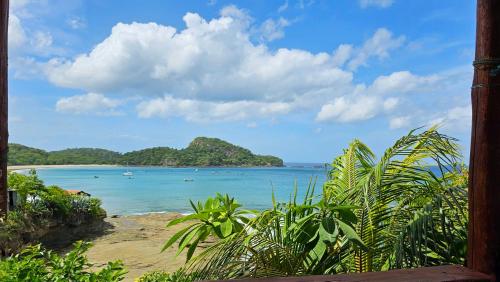 a view of a beach with boats in the water at Monkey House Hostel in Tola