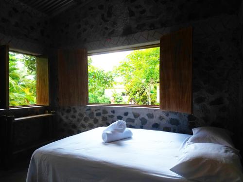 a bed with a towel on it in a room with two windows at Cabañas Ixaya in Catemaco