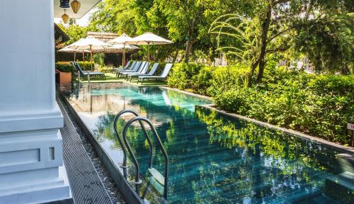 a swimming pool with chairs and umbrellas in a resort at Hoi An Odyssey Hotel & Spa in Hoi An