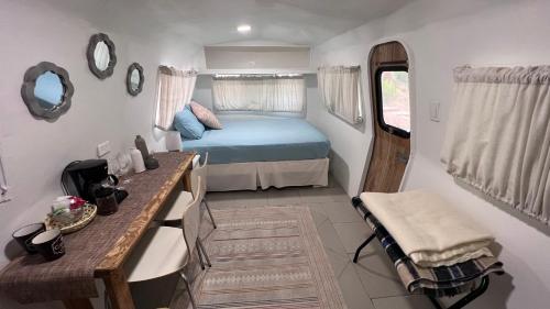 バジェ・デ・グアダルーペにあるRancho Matalote en Valle de Guadalupeのベッドとテーブルが備わる小さな客室です。