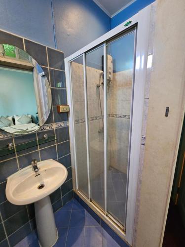 a bathroom with a shower and a sink and a mirror at Samsen Sam Place in Bangkok