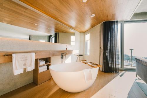 eine große weiße Badewanne im Bad mit einem großen Fenster in der Unterkunft Nest Hotel Incheon in Incheon