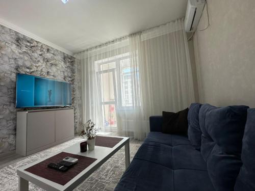 sala de estar con sofá azul y TV en Grand Turan , Turan 43, en Taldykolʼ