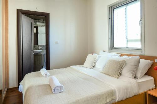 ein großes weißes Bett in einem Zimmer mit Fenster in der Unterkunft Simple Living in Netanya Center by Sea N' Rent in Netanya