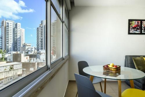 einen Tisch und Stühle in einem Zimmer mit einem großen Fenster in der Unterkunft Simple Living in Netanya Center by Sea N' Rent in Netanya