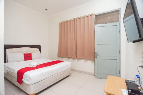 a bedroom with a bed and a television in it at RedDoorz Plus near RS PMI Bogor in Bogor