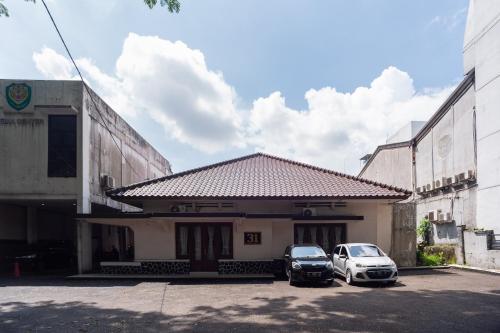 two cars parked in a parking lot in front of a building at RedDoorz Plus near RS PMI Bogor in Bogor
