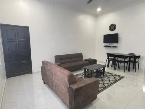 een woonkamer met een bank en een tafel bij 13 Avenue Homestay in Kota Bharu