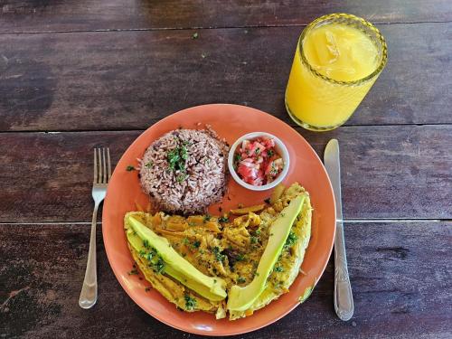 a plate of food on a wooden table with a drink at Monkey House Hostel in Tola