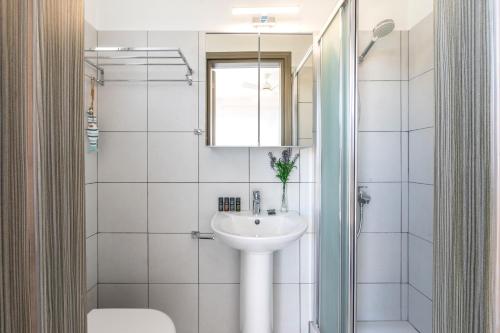 een witte badkamer met een wastafel en een spiegel bij Ayia Thekla Seafront Villa Dagi in Ayia Napa