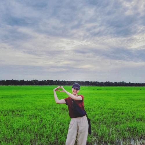 a young man standing in a green field at Bamboo Eco Village in Can Tho