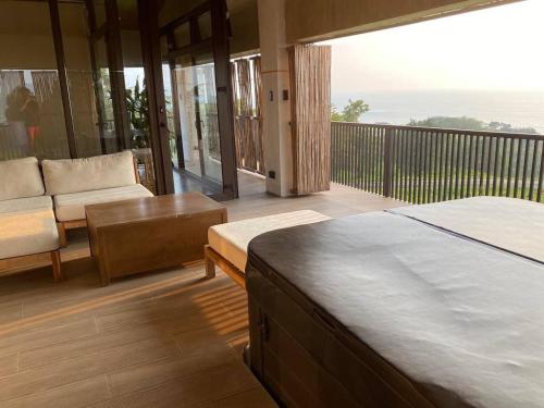 a bedroom with a balcony with a bed and a couch at Brisa de Cristal at Canyon Cove Nasugbu Batangas in Nasugbu