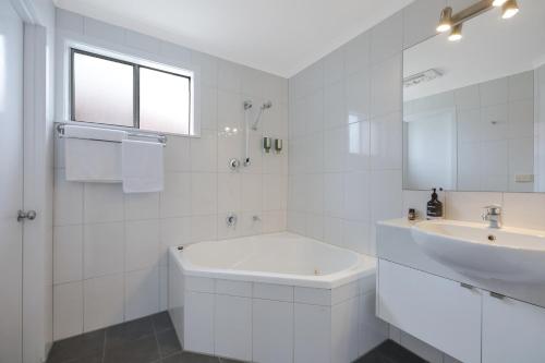 a white bathroom with a tub and a sink at Hamilton Townhouse Motel in Hamilton