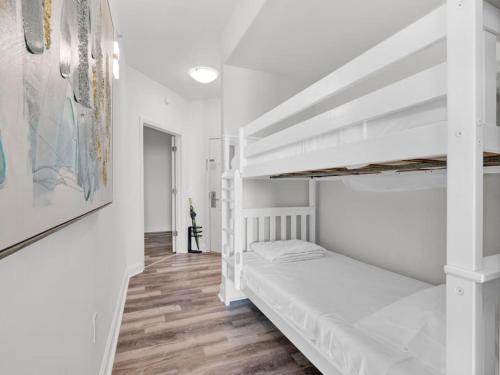 ein Schlafzimmer mit einem weißen Etagenbett und Holzböden in der Unterkunft Huge Pool, Sunrise Lakeview 12th floor near Disney in Orlando