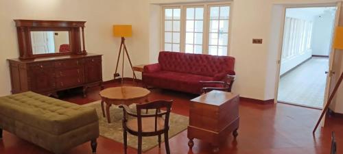 a living room with a red couch and a table at Lockhart Bungalow Munnar - A CGH Earth SAHA Experience in Munnar