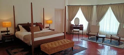a bedroom with a bed and a chair and a mirror at Lockhart Bungalow Munnar - A CGH Earth SAHA Experience in Munnar