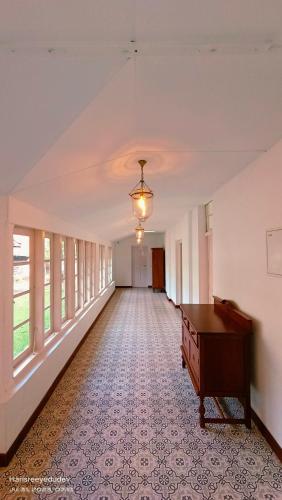 an empty hallway with a table and windows at Lockhart Bungalow Munnar - A CGH Earth SAHA Experience in Munnar