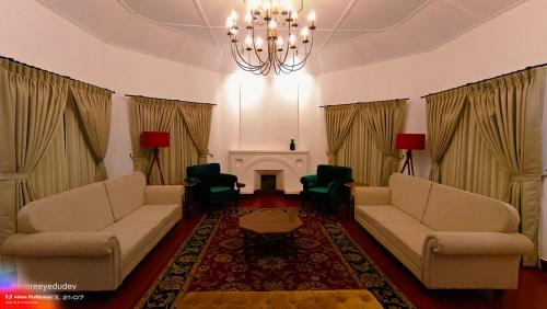 a living room with two couches and a chandelier at Lockhart Bungalow Munnar - A CGH Earth SAHA Experience in Munnar