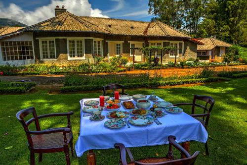 a table with plates of food on it in front of a house at Lockhart Bungalow Munnar - A CGH Earth SAHA Experience in Munnar