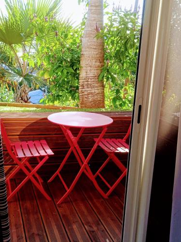a red table and two chairs on a porch at Le vol du Papangue in Saint-Pierre