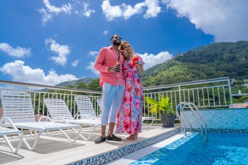 a man and woman standing on a deck next to a swimming pool at Lakaz Kreol in Beau Vallon