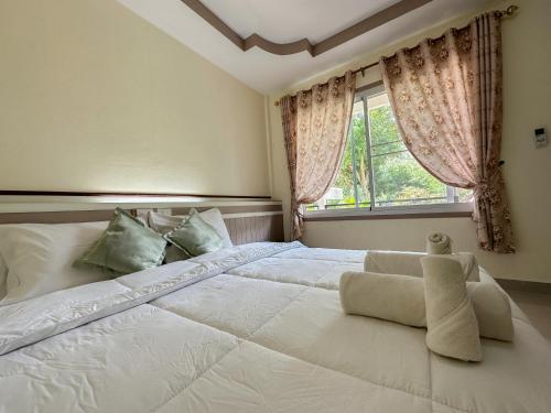 a bedroom with a large white bed with a window at ชอว์ งาทอง รีสอร์ต Chor Ngar Thong Erawan in Kanchanaburi City