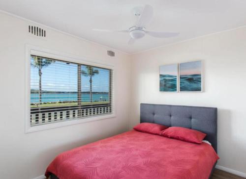 a bedroom with a red bed and a window at Lakeside 5 in Tuncurry