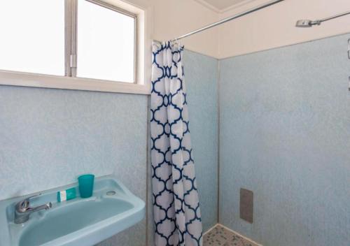 a bathroom with a shower curtain and a sink at Lakeside 5 in Tuncurry