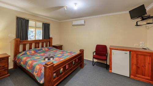 une chambre avec un lit et une chaise rouge dans l'établissement White Cliffs Hotel, à White Cliffs