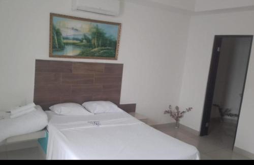 a white bed in a room with a painting on the wall at Hotel Grecia Costa Rica in Grecia