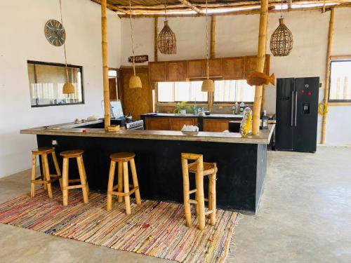 eine große Küche mit einer Theke und Stühlen in der Unterkunft El Mirador de Máncora in Máncora