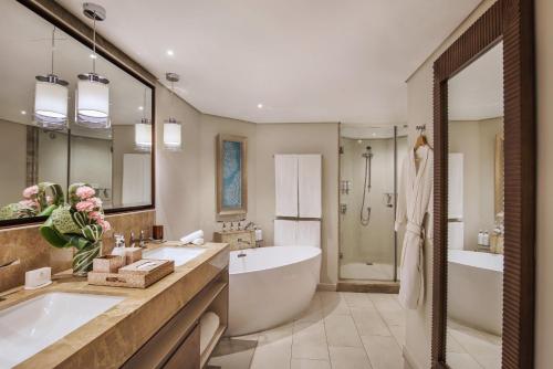 a bathroom with two sinks and a tub and a bath tub at Royal Palm Beachcomber Luxury in Grand Baie