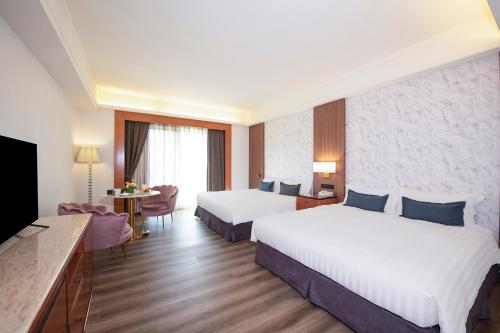 ein Hotelzimmer mit 2 Betten und einem TV in der Unterkunft Hamp Court Palace Taipei in Taipeh