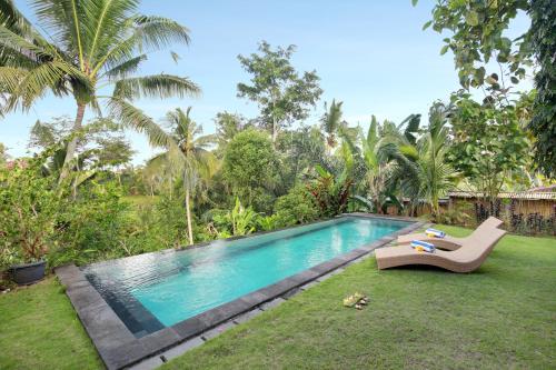 a swimming pool in a yard with a chair next to it at Villa with amazing rice field view between Canggu and Ubud in Penebel