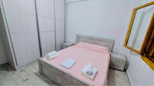 a small bedroom with a pink bed with a mirror at Dhermi Village Apartments in Dhërmi