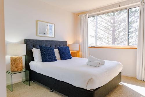 a bedroom with a bed with blue pillows and a window at Grandview Apartments in Ballina