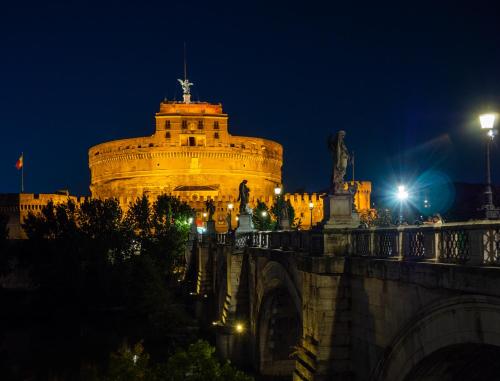 a lit up building with a statue on a bridge at night at Alto Apartment in Rome