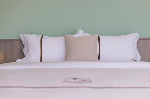 a bed with white pillows and white sheets at Penghu Swing Sea Homestay in Magong