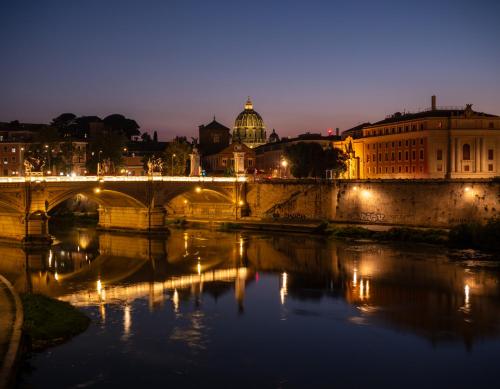 a bridge over a river with a city at night at Alto Apartment in Rome