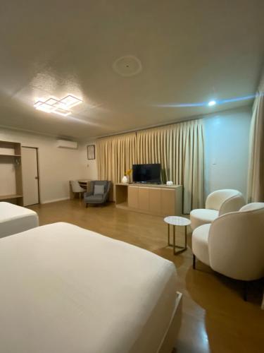 a hotel room with a bed and chairs and a television at Honey Suite Room Inside Bee Cafe Cebu at Ayala Area in Cebu City